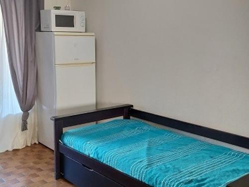 un lit avec un micro-ondes au-dessus d'un réfrigérateur dans l'établissement Studio avec loggia et jardin, piscine et tennis, 500m de la mer - Argelès-sur-Mer - FR-1-776-60, à Argelès-sur-Mer