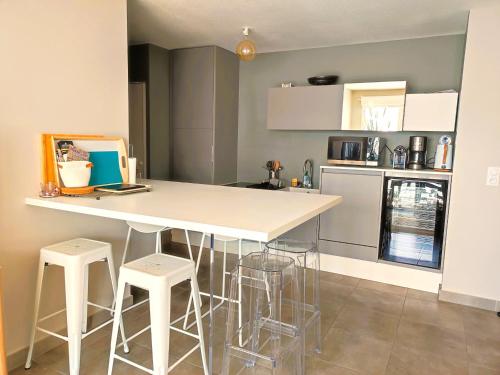 une cuisine avec un comptoir blanc et des tabourets dans l'établissement Superbe Appartement 6 Pers. à Argelès: Terrasse, WIFI, Parking, Proche Plage - FR-1-776-25, à Argelès-sur-Mer