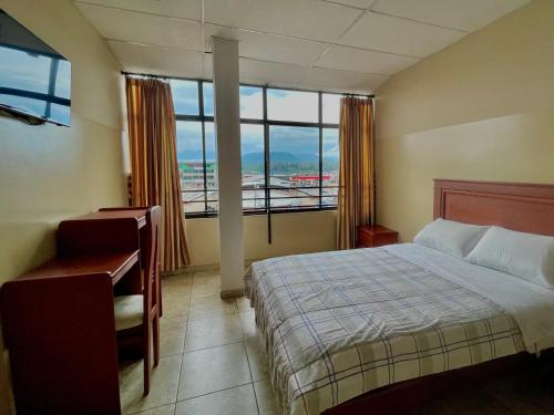 a bedroom with a bed and a desk and a window at Hotel Río Tena in Tena