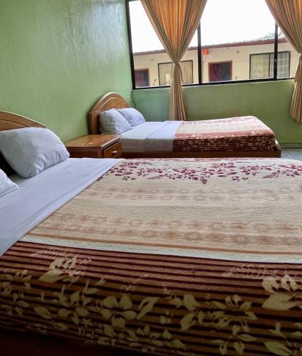 two beds in a hotel room with a window at Hotel Río Tena in Tena