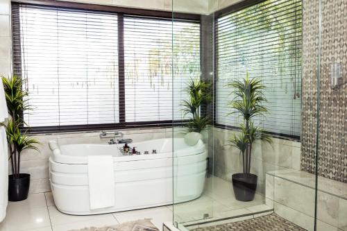 ein Badezimmer mit einer großen Badewanne und Topfpflanzen in der Unterkunft One O Eight Boutique Hotel in Benoni