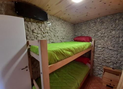 Alquiler playa Quequén في قويقوين: سريرين بطابقين في غرفة مع جدار حجري