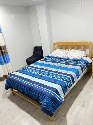 uma cama com um cobertor azul e branco em Mariandes Hostel em Huaraz