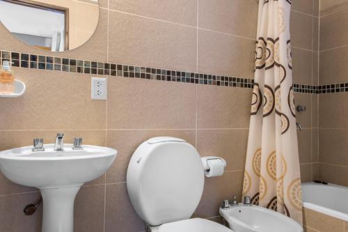 La salle de bains est pourvue de toilettes, d'un lavabo et d'un miroir. dans l'établissement Rivendell Bungalows Bariloche, à San Carlos de Bariloche