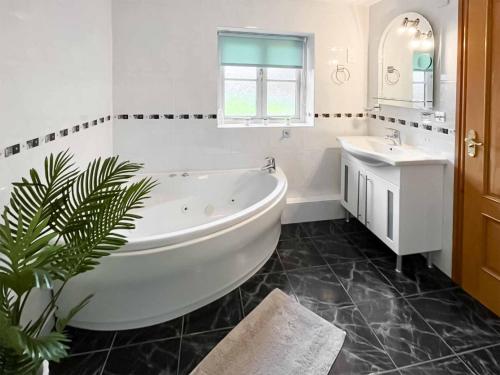 a white bathroom with a tub and a sink at Glanllyn Lodge in Llanuwchllyn