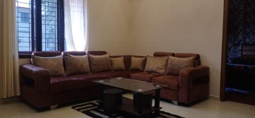 un soggiorno con divano marrone e tavolo di IMARA a Mangalore