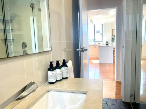 three bottles of wine sitting on a counter in a bathroom at Perfect Randwick Escape -2Bdrm-Parking - Walk To Hospital & Shops in Sydney
