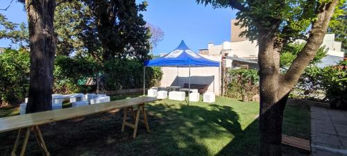uma tenda azul com cadeiras e uma mesa num quintal em La casita de Aitana em Pergamino