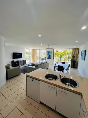 a large kitchen with two sinks and a living room at at Marina Shores in Airlie Beach