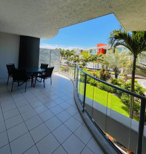 a balcony with a table and chairs and palm trees at at Marina Shores in Airlie Beach