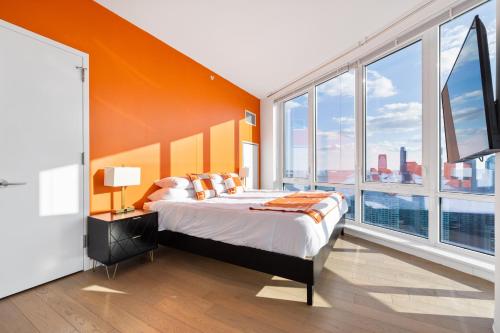 1 dormitorio con 1 cama con pared de color naranja y ventanas grandes en Tallest Penthouse in NJ with Wraparound Balcony, en Hoboken