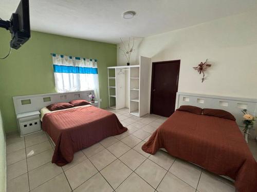 two beds in a room with green walls at Terraza del Lago in Tequesquitengo