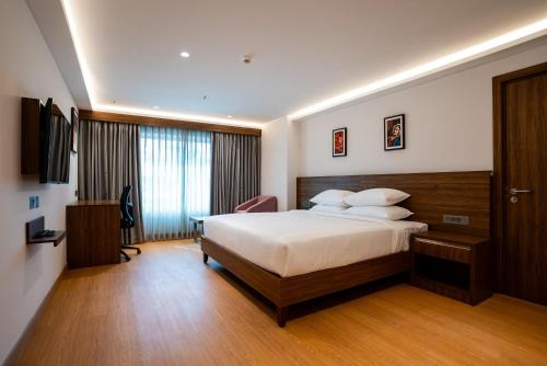 a hotel room with a bed and a desk at Lilac Hotel Guruvayur in Guruvāyūr