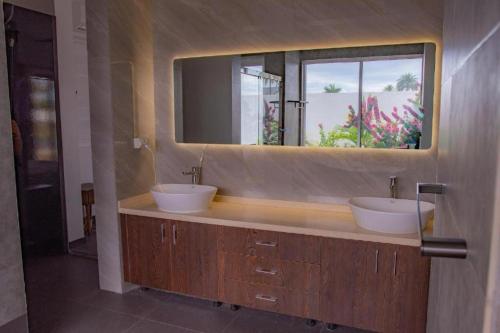 baño con 2 lavabos y espejo grande en Island Villa en Nadi