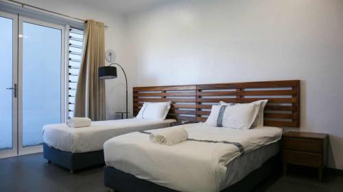 two beds in a hotel room with a window at Island Villa in Nadi