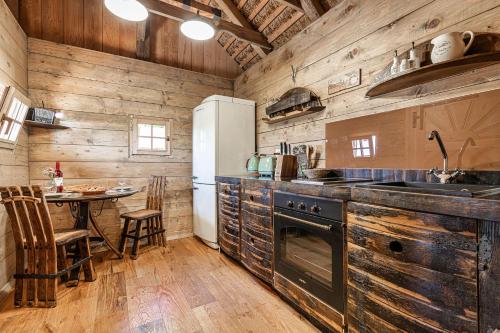 cocina con paredes de madera, mesa y nevera en Vineyard Cottages Skatlar - Happy Rentals en Otočec