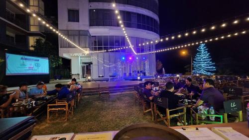 a group of people sitting at tables in front of a stage at Blu Hotel in Nakhon Phanom