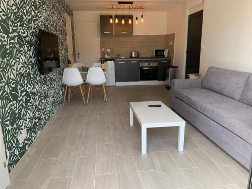 un salon avec un canapé et une table et une cuisine dans l'établissement bellucciu di porto vecchio***. (Piscine chauffée), à Porto-Vecchio