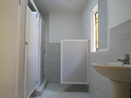 W białej łazience znajduje się umywalka i lustro. w obiekcie Hostal Familiar Caribbean Blu w mieście Cartagena de Indias