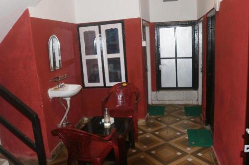 uma casa de banho com paredes vermelhas, um lavatório e uma cadeira. em Yours Family Restaurant and Homestay em Deorāli