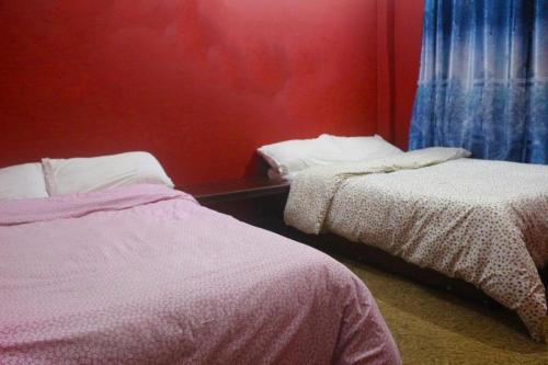 um quarto com 2 camas e uma parede vermelha em Yours Family Restaurant and Homestay em Deorāli