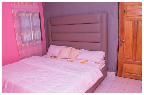 Cama en habitación con rosa y púrpura en RÉSIDENCE COLETTE en Bafoussam
