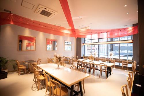 una sala da pranzo con tavoli, sedie e finestre di Hotel Dans Le Coeur Osaka Umeda ad Osaka