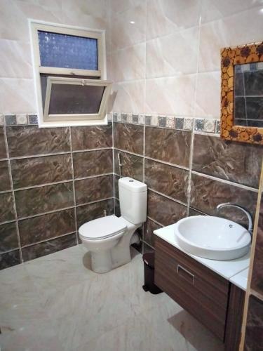 a bathroom with a toilet and a sink and a window at شقة الزمالك علي النيل حي السفارات in Cairo