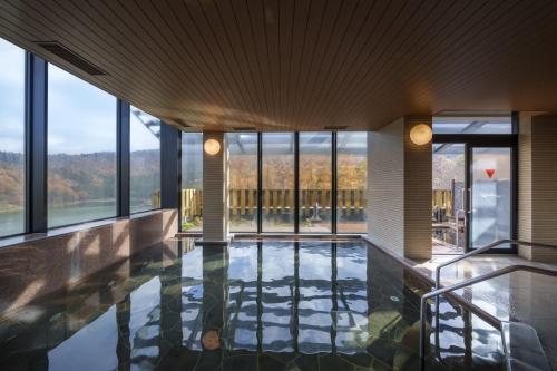 a pool in a building with windows at HOKURYUKO HOTEL North NAGANO in Iiyama