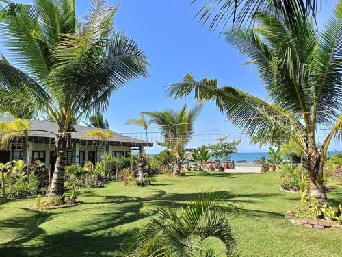 a house with palm trees in front of the ocean at Marand Beach Resort in Bauang