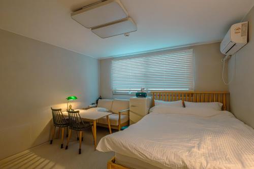 um quarto com uma cama, uma mesa e uma secretária em Marie's House 102 Hongdae em Seul
