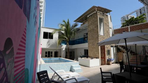una piscina con sillas y una sombrilla junto a un edificio en CASA BELLAMARE, en Cartagena de Indias