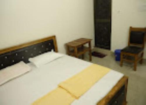 a bedroom with a bed and a chair and a desk at Shree Harshan Kutir , Ayodhya in Ayodhya