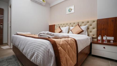una camera da letto con un grande letto con asciugamani di La Serene Business Hotel a Bangalore