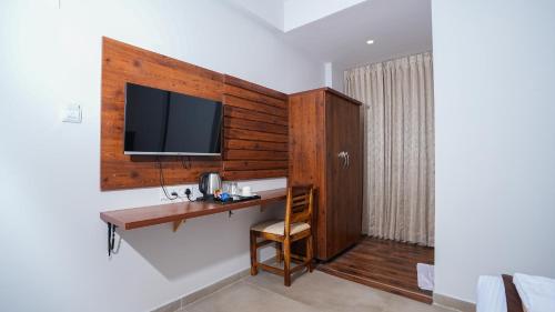 um quarto com uma secretária e uma televisão na parede em La Serene Business Hotel em Bangalore