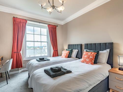 2 camas en un dormitorio con cortinas rojas en Eversley, en Llandudno