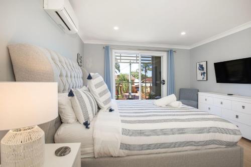 a bedroom with a bed and a couch and a television at Bluewater Jervis Bay - Pet Friendly with Spa in Callala Beach