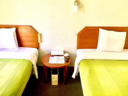 Habitación con 2 camas y mesa con teléfono. en Hotel Happy Holiday Ishigakijima - Vacation STAY 04133v, en Ishigaki Island