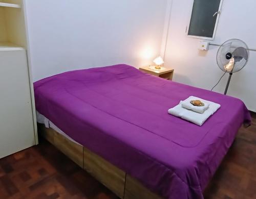 a purple bed with a towel on top of it at CASA MAYO - Mini DEPTO 2 AMB - BAÑO COMPARTIDO in Buenos Aires