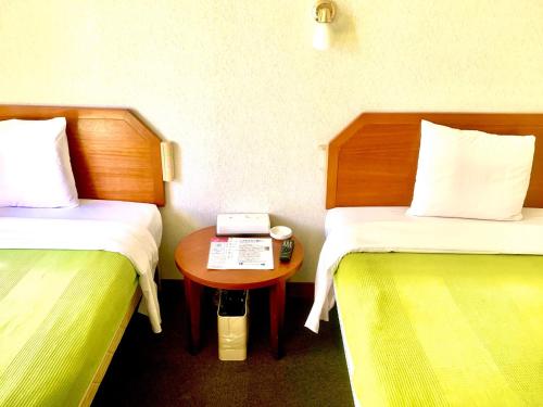 a room with two beds and a table with a telephone at Hotel Happy Holiday Ishigakijima - Vacation STAY 04135v in Ishigaki Island