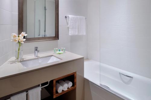 a white bathroom with a sink and a bath tub at Courtyard by Marriott World Trade Center, Abu Dhabi in Abu Dhabi