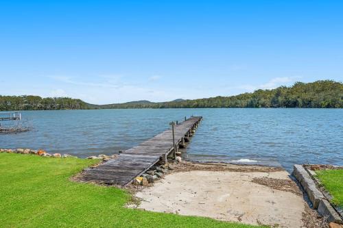 a wooden dock in the middle of a lake at Mirror Bay in Laurieton