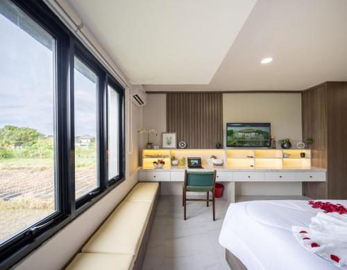 a bedroom with a bed and a desk and windows at Verdant Bali Sekar Sari in Denpasar