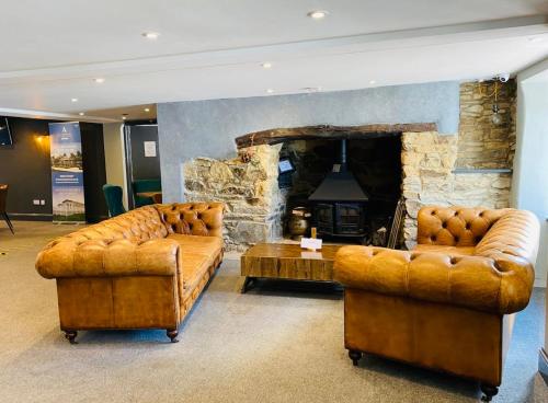 a living room with two couches and a stone fireplace at C-Scape Lodge in Newquay