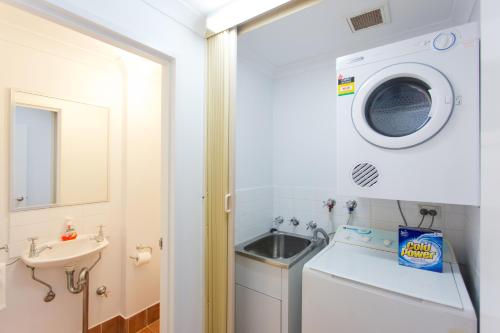 a small bathroom with a sink and a washing machine at Windows on Pakenham-Hip art space in the West End in Fremantle