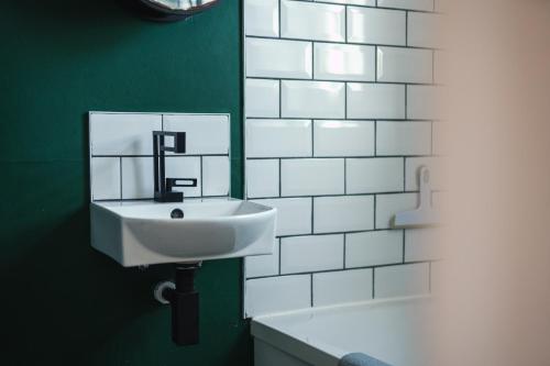 lavabo blanco en un baño verde con espejo en Stay with airhgt at 3 bedroom house near The Stray en Harrogate
