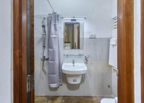 a white bathroom with a sink and a mirror at Kerawalapitiya Resort in Mahabage
