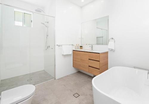 a white bathroom with a toilet and a sink at Southcape, Gerroa in Gerroa