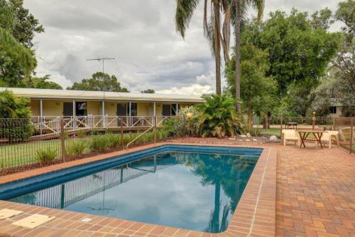 a swimming pool in front of a house at Tambo Mill Motel & Caravan Park in Tambo
