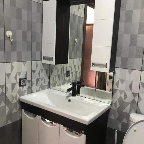 ein Badezimmer mit einem weißen Waschbecken und einem Spiegel in der Unterkunft Квартира in Almaty